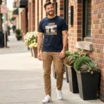 Homme portant un tee shirt Liberto bleu marine décontracté sur un trottoir urbain ensoleillé, tenue casual et détendue